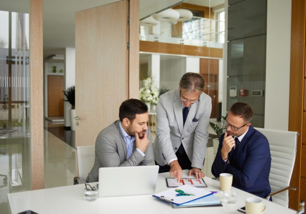 Three businessmen discussing documents in office.