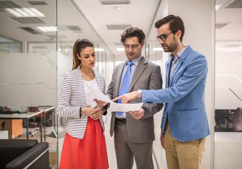Three colleagues discussing documents in office.